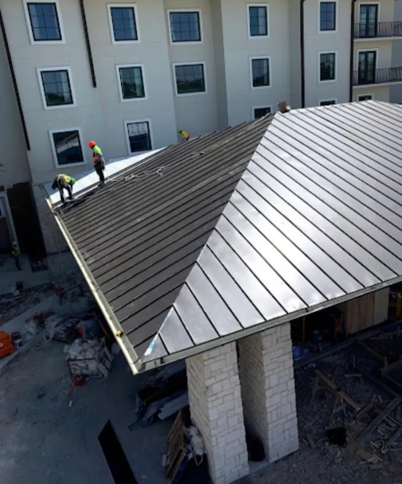 Crew installing standing seam metal roof panels on a commercial project in Locust